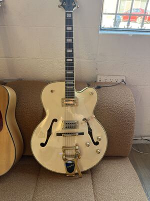 Item 1: cream hollowbody electric guitar with a Bigsby vibrato